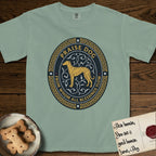 Praise Dog From Whom All Blessings Flow Galgo T-Shirt flat lay in Bay, featuring a gold and navy oval medallion with a brindle Galgo standing in profile over silver filigree vines, a knotwork border, and the words Praise Dog From Whom All Blessings Flow.