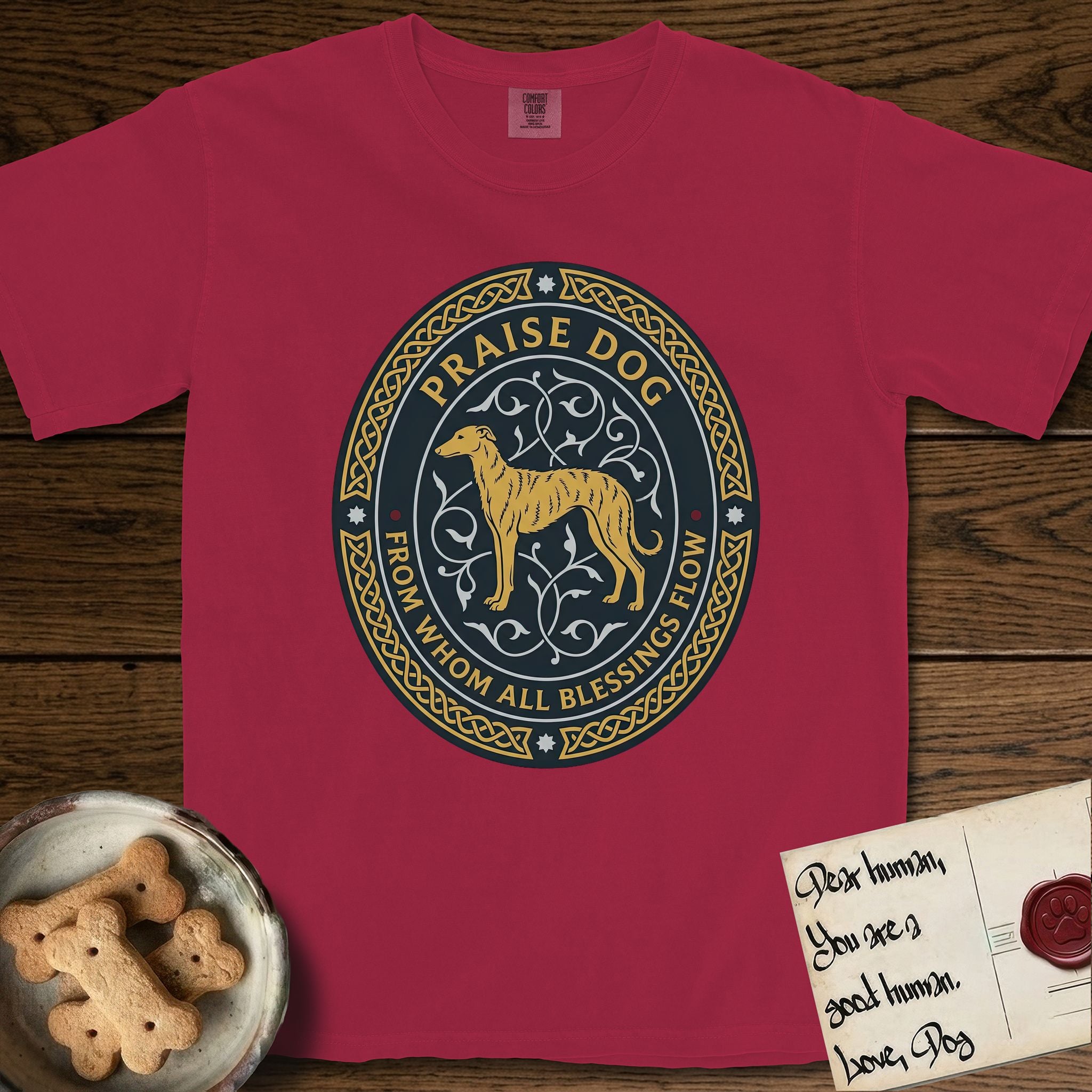 Praise Dog From Whom All Blessings Flow Galgo T-Shirt flat lay in Chili, featuring a gold and navy oval medallion with a brindle Galgo standing in profile over silver filigree vines, a knotwork border, and the words Praise Dog From Whom All Blessings Flow.