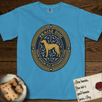 Praise Dog From Whom All Blessings Flow Galgo T-Shirt flat lay in Royal Caribe, featuring a gold and navy oval medallion with a brindle Galgo standing in profile over silver filigree vines, a knotwork border, and the words Praise Dog From Whom All Blessings Flow.