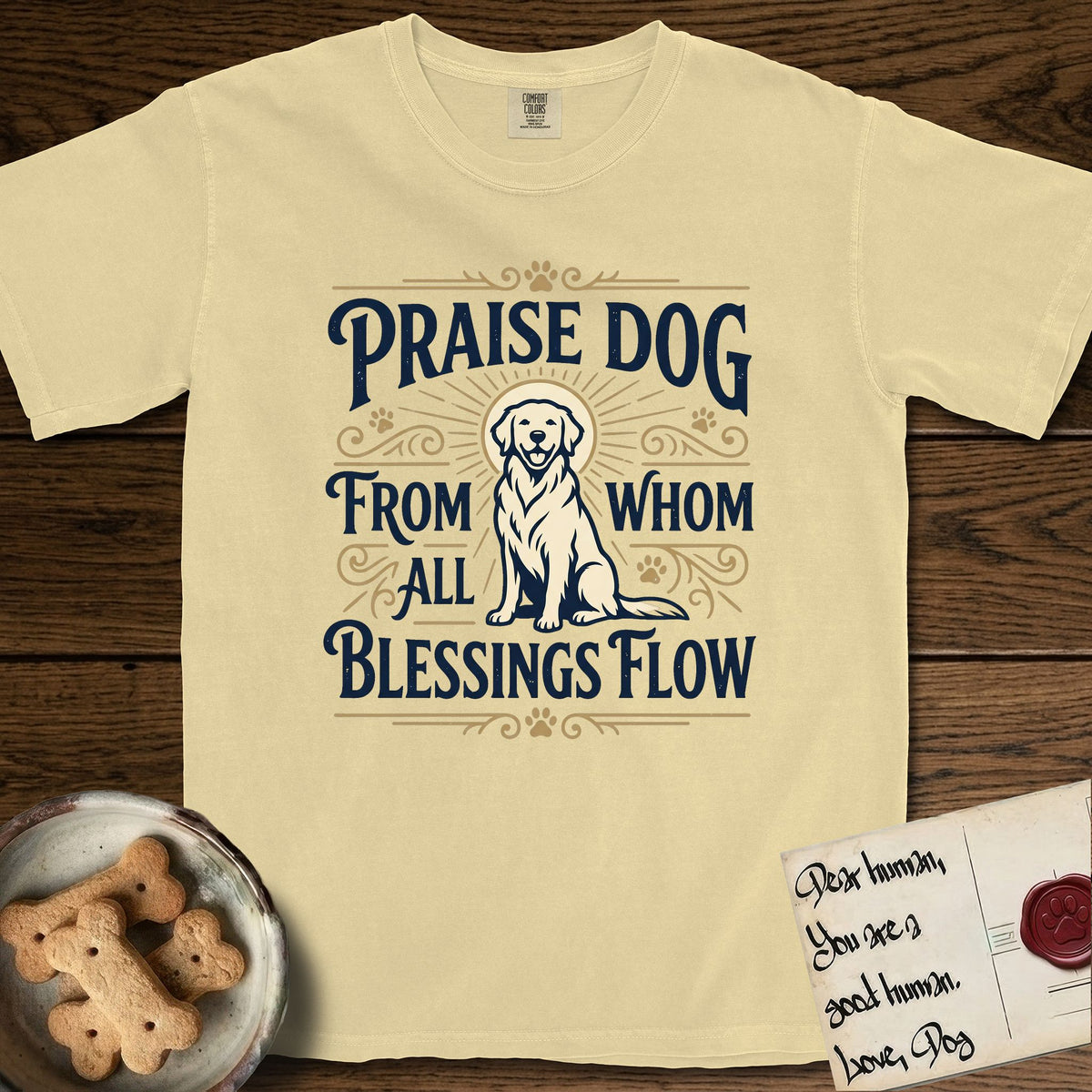 Praise Dog From Whom All Blessings Flow Golden Retriever T-Shirt flat lay in Butter, featuring a bold Western hand-lettered "Praise Dog" design in navy and gold with a haloed Golden Retriever at center.