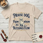 Praise Dog From Whom All Blessings Flow Golden Retriever T-Shirt flat lay in Sand, featuring a bold Western hand-lettered "Praise Dog" design in navy and gold with a haloed Golden Retriever at center.