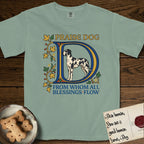Praise Dog From Whom All Blessings Flow Great Dane T-Shirt flat lay in Bay, featuring an illuminated manuscript capital D in blue and gold with a harlequin Great Dane standing inside the letter and the words Praise Dog From Whom All Blessings Flow.