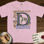 Praise Dog From Whom All Blessings Flow Great Dane T-Shirt flat lay in Blossom, featuring an illuminated manuscript capital D in blue and gold with a harlequin Great Dane standing inside the letter and the words Praise Dog From Whom All Blessings Flow.