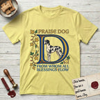 Praise Dog From Whom All Blessings Flow Great Dane T-Shirt flat lay in Cornsilk, featuring an illuminated manuscript capital D in blue and gold with a harlequin Great Dane standing inside the letter and the words Praise Dog From Whom All Blessings Flow.