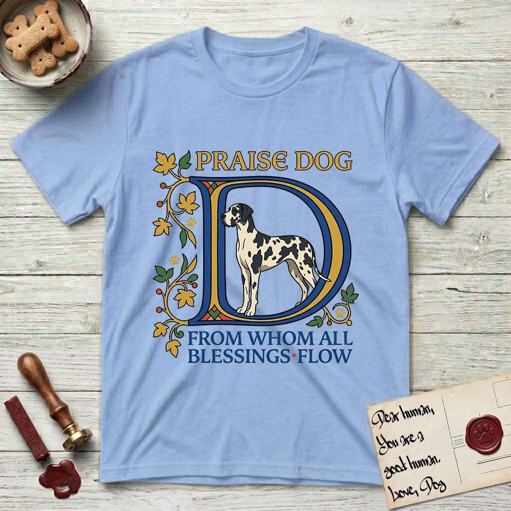 Praise Dog From Whom All Blessings Flow Great Dane T-Shirt flat lay in Light Blue, featuring an illuminated manuscript capital D in blue and gold with a harlequin Great Dane standing inside the letter and the words Praise Dog From Whom All Blessings Flow.
