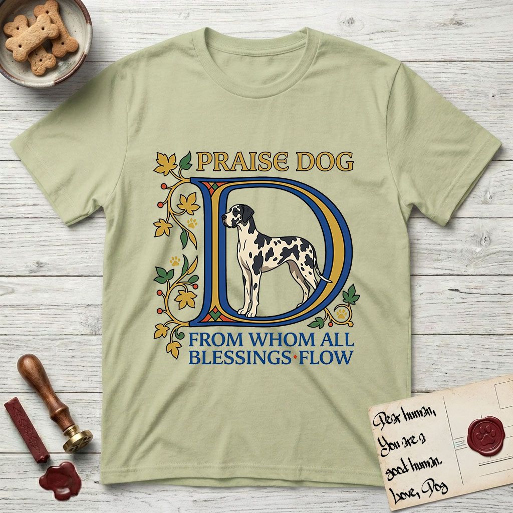 Praise Dog From Whom All Blessings Flow Great Dane T-Shirt flat lay in Pistachio, featuring an illuminated manuscript capital D in blue and gold with a harlequin Great Dane standing inside the letter and the words Praise Dog From Whom All Blessings Flow.