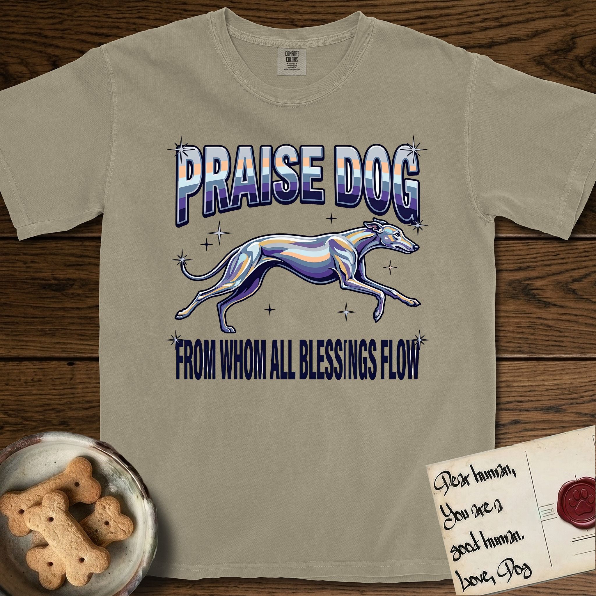 Praise Dog From Whom All Blessings Flow Greyhound T-Shirt flat lay in Khaki, featuring a retro chrome airbrush design with a Greyhound running at full stretch among sparkle stars and the words Praise Dog From Whom All Blessings Flow in chrome sunset lettering.
