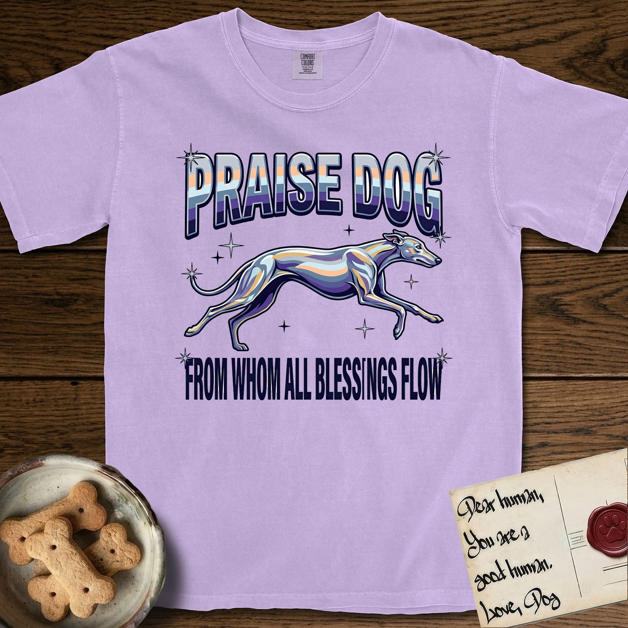 Praise Dog From Whom All Blessings Flow Greyhound T-Shirt flat lay in Orchid, featuring a retro chrome airbrush design with a Greyhound running at full stretch among sparkle stars and the words Praise Dog From Whom All Blessings Flow in chrome sunset lettering.