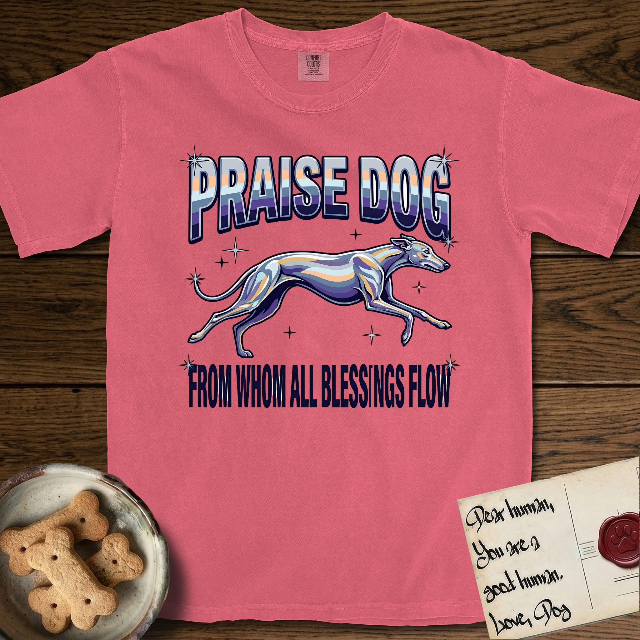 Praise Dog From Whom All Blessings Flow Greyhound T-Shirt flat lay in Watermelon, featuring a retro chrome airbrush design with a Greyhound running at full stretch among sparkle stars and the words Praise Dog From Whom All Blessings Flow in chrome sunset lettering.