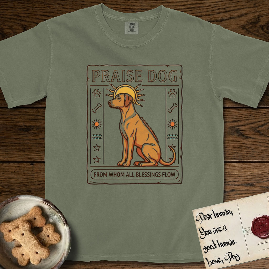 Praise Dog From Whom All Blessings Flow Rhodesian Ridgeback T-Shirt flat lay in Sage, featuring an ancient Egyptian carved-relief emblem of a Rhodesian Ridgeback in side profile with a visible spine ridge, a rayed golden sun halo, hieroglyph glyph columns, and a ragged stone border with "Praise Dog From Whom All Blessings Flow" lettering.
