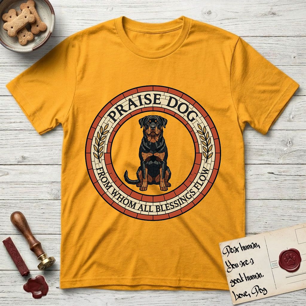 Praise Dog From Whom All Blessings Flow Rottweiler T-Shirt flat lay in Gold, featuring a Roman mosaic ring medallion of a seated Rottweiler with natural ears and a full undocked tail, built from terracotta and mahogany tiles and flanked by laurel branches, with "Praise Dog From Whom All Blessings Flow" lettering.