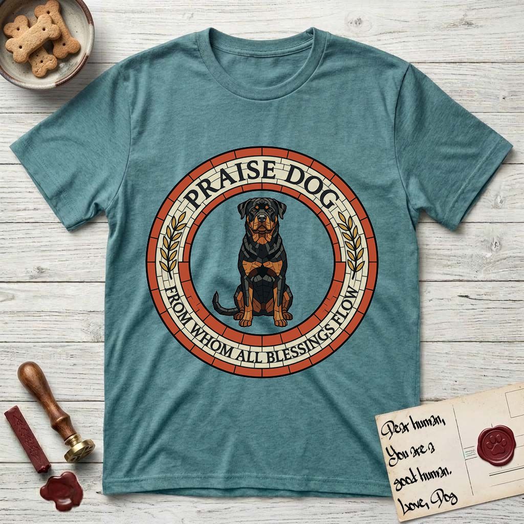 Praise Dog From Whom All Blessings Flow Rottweiler T-Shirt flat lay in Heather Galapagos Blue, featuring a Roman mosaic ring medallion of a seated Rottweiler with natural ears and a full undocked tail, built from terracotta and mahogany tiles and flanked by laurel branches, with "Praise Dog From Whom All Blessings Flow" lettering.