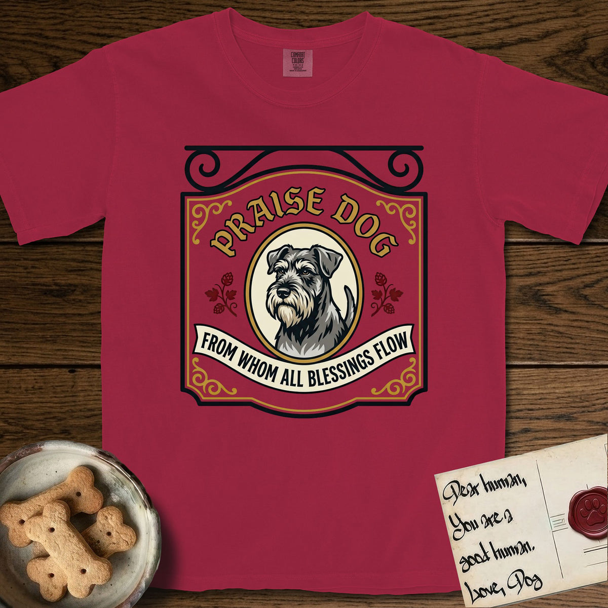 Praise Dog From Whom All Blessings Flow Schnauzer T-Shirt flat lay in Chili, featuring a vintage tavern sign with a bearded Schnauzer portrait in a gilded oval, hops sprigs, and a ribbon banner, with the words Praise Dog From Whom All Blessings Flow.