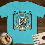 Praise Dog From Whom All Blessings Flow Schnauzer T-Shirt flat lay in Lagoon Blue, featuring a vintage tavern sign with a bearded Schnauzer portrait in a gilded oval, hops sprigs, and a ribbon banner, with the words Praise Dog From Whom All Blessings Flow.