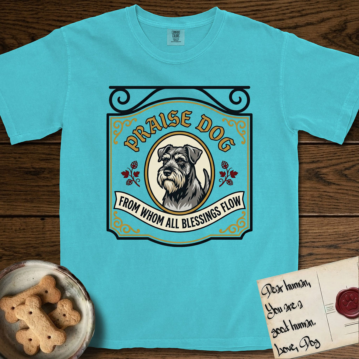 Praise Dog From Whom All Blessings Flow Schnauzer T-Shirt flat lay in Lagoon Blue, featuring a vintage tavern sign with a bearded Schnauzer portrait in a gilded oval, hops sprigs, and a ribbon banner, with the words Praise Dog From Whom All Blessings Flow.