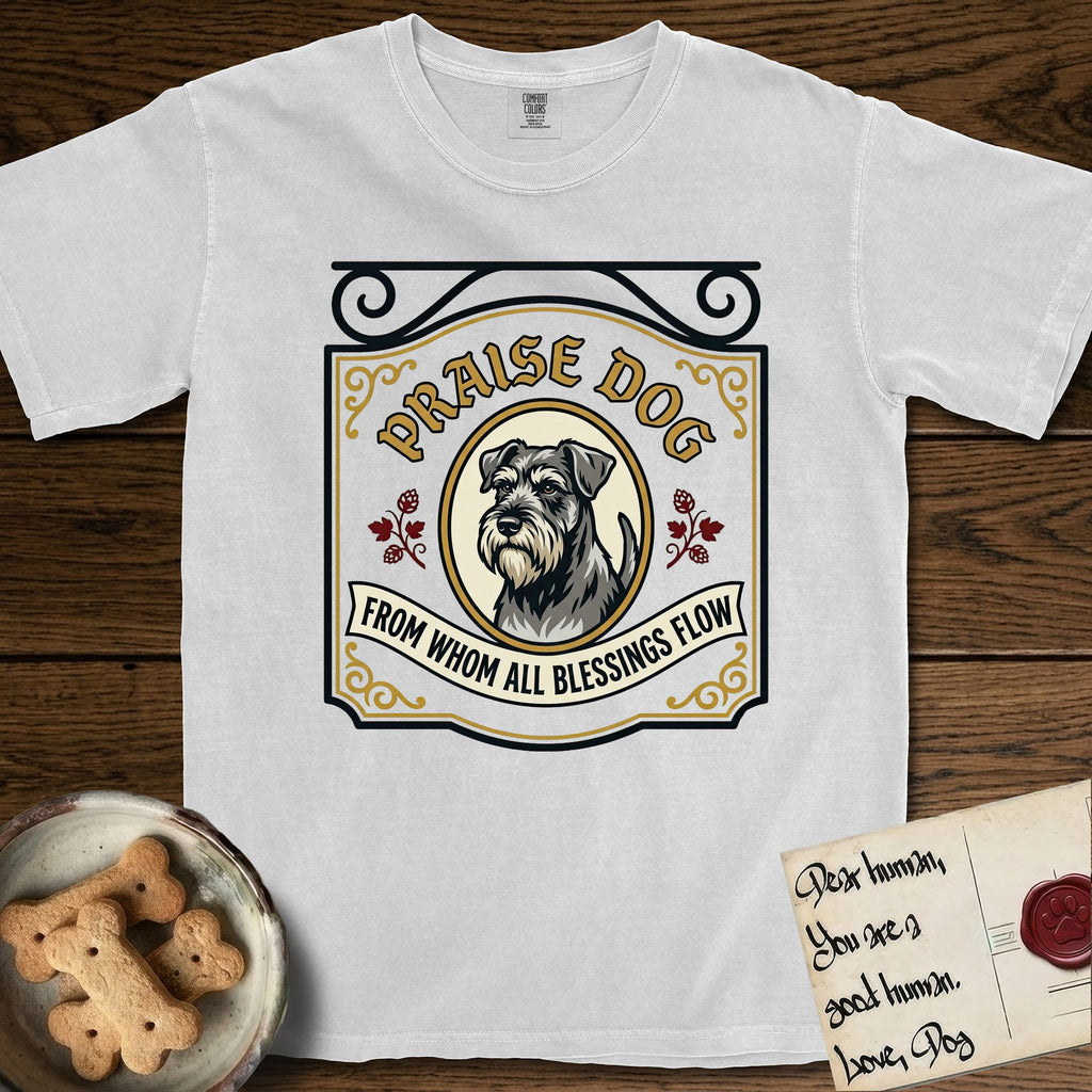 Praise Dog From Whom All Blessings Flow Schnauzer T-Shirt flat lay in White, featuring a vintage tavern sign with a bearded Schnauzer portrait in a gilded oval, hops sprigs, and a ribbon banner, with the words Praise Dog From Whom All Blessings Flow.