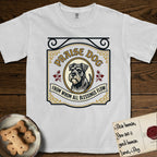 Praise Dog From Whom All Blessings Flow Schnauzer T-Shirt flat lay in White, featuring a vintage tavern sign with a bearded Schnauzer portrait in a gilded oval, hops sprigs, and a ribbon banner, with the words Praise Dog From Whom All Blessings Flow.
