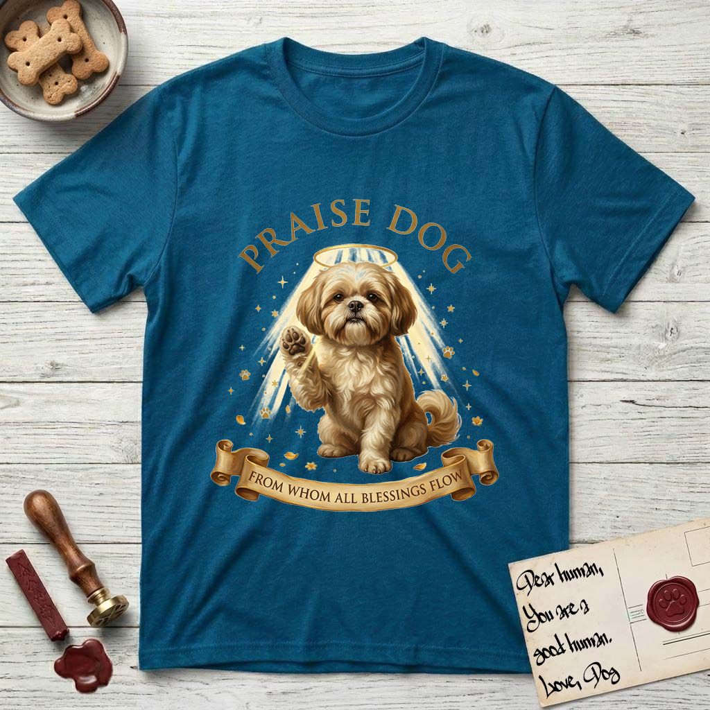 Praise Dog From Whom All Blessings Flow Shih Tzu T-Shirt flat lay in Antique Sapphire, featuring an old-master devotional oil painting of a Shih Tzu seated with one paw raised in blessing, a floating gold halo and streaming light, a shower of small gold blessings, and gilt "Praise Dog From Whom All Blessings Flow" lettering on a ribbon scroll.