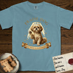Praise Dog From Whom All Blessings Flow Shih Tzu T-Shirt flat lay in Ice Blue, featuring an old-master devotional oil painting of a Shih Tzu seated with one paw raised in blessing, a floating gold halo and streaming light, a shower of small gold blessings, and gilt "Praise Dog From Whom All Blessings Flow" lettering on a ribbon scroll.