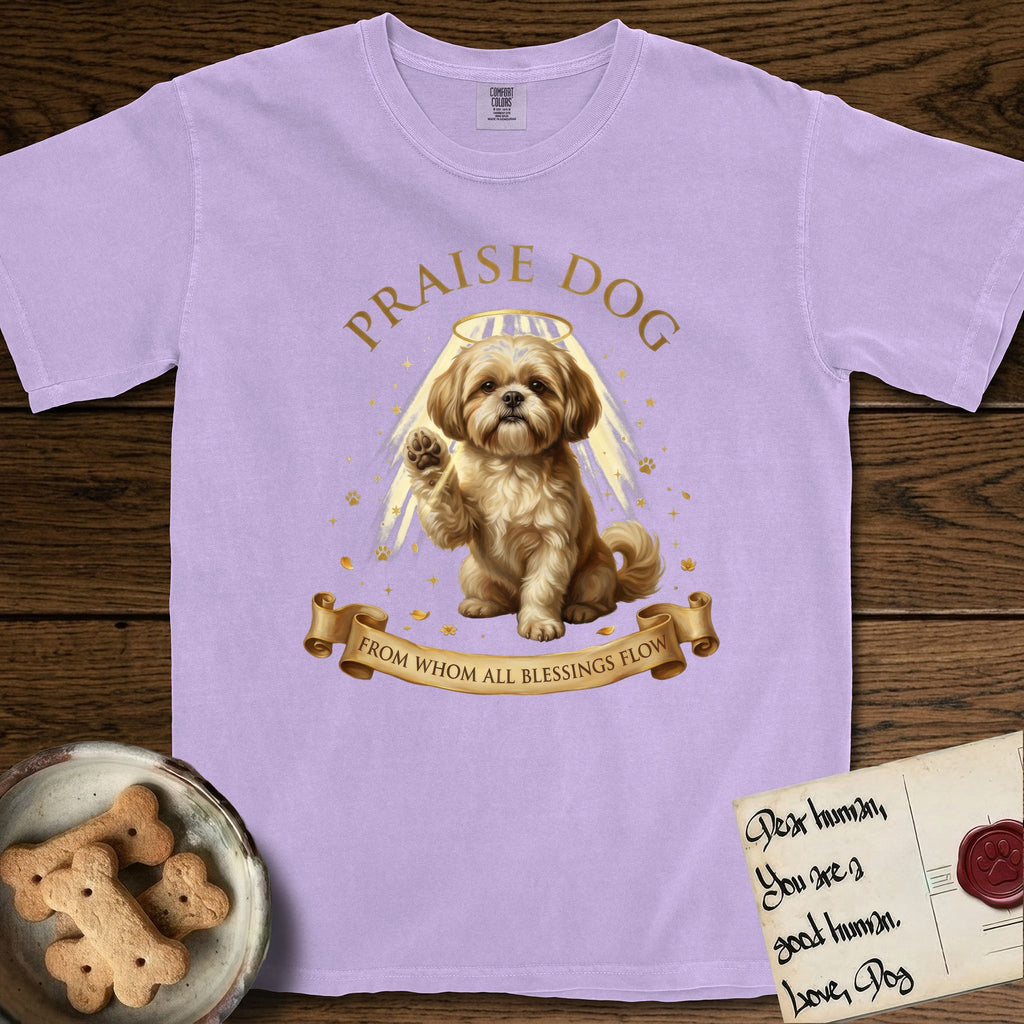 Praise Dog From Whom All Blessings Flow Shih Tzu T-Shirt flat lay in Orchid, featuring an old-master devotional oil painting of a Shih Tzu seated with one paw raised in blessing, a floating gold halo and streaming light, a shower of small gold blessings, and gilt "Praise Dog From Whom All Blessings Flow" lettering on a ribbon scroll.