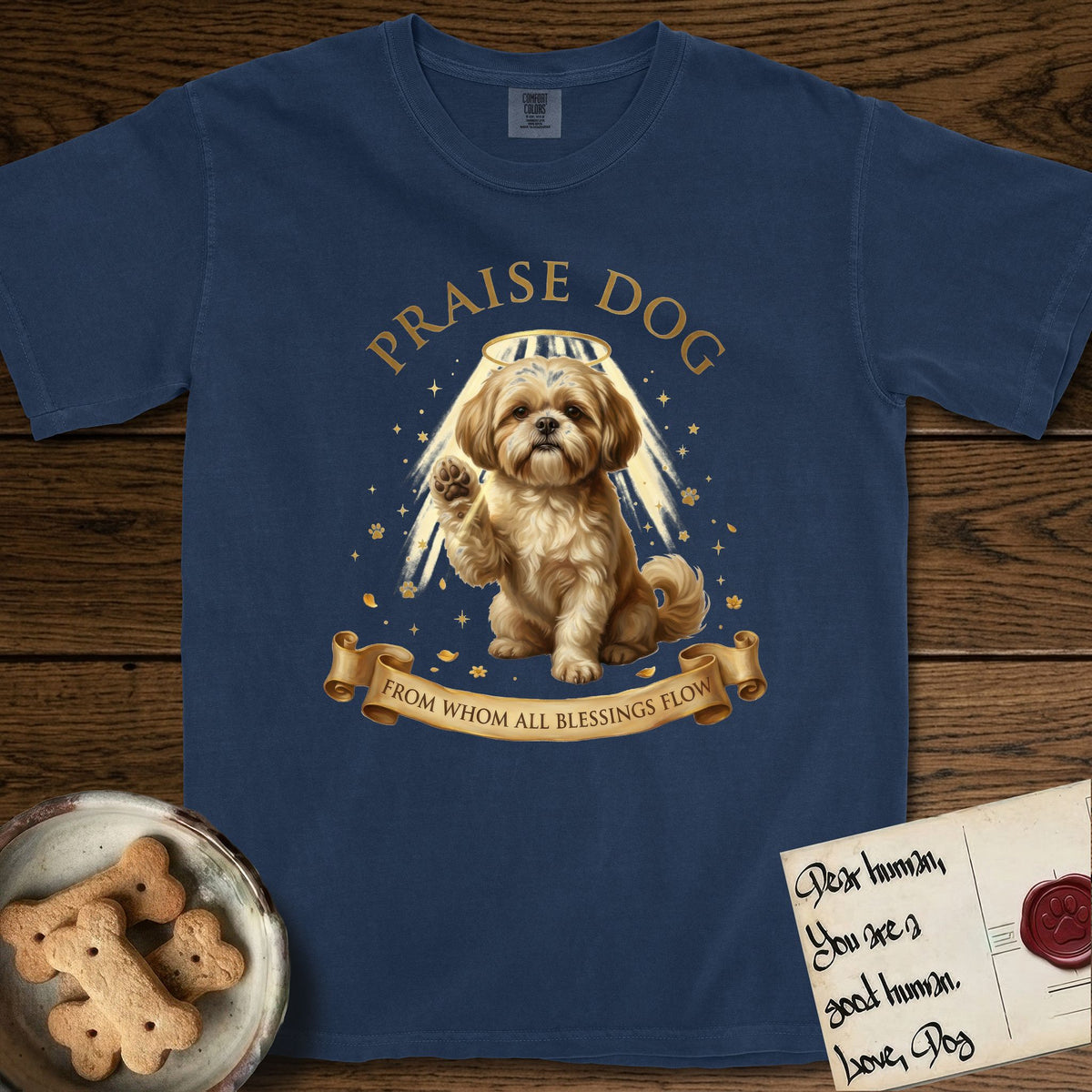 Praise Dog From Whom All Blessings Flow Shih Tzu T-Shirt flat lay in True Navy, featuring an old-master devotional oil painting of a Shih Tzu seated with one paw raised in blessing, a floating gold halo and streaming light, a shower of small gold blessings, and gilt "Praise Dog From Whom All Blessings Flow" lettering on a ribbon scroll.