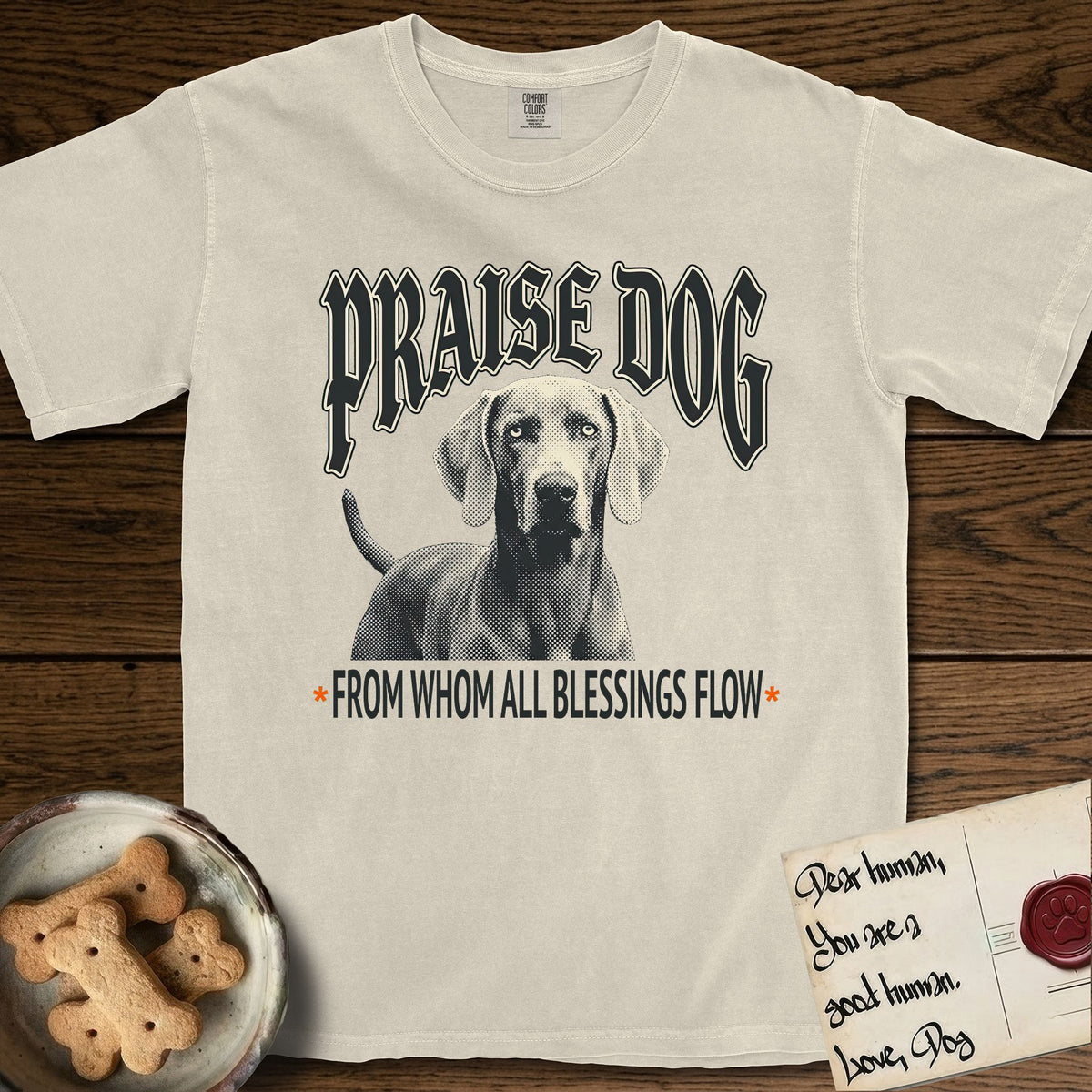 Praise Dog From Whom All Blessings Flow Weimaraner T-Shirt flat lay in Ivory, featuring a gothic halftone poster with a Weimaraner staring straight ahead beneath heavy blackletter lettering and the words Praise Dog From Whom All Blessings Flow.