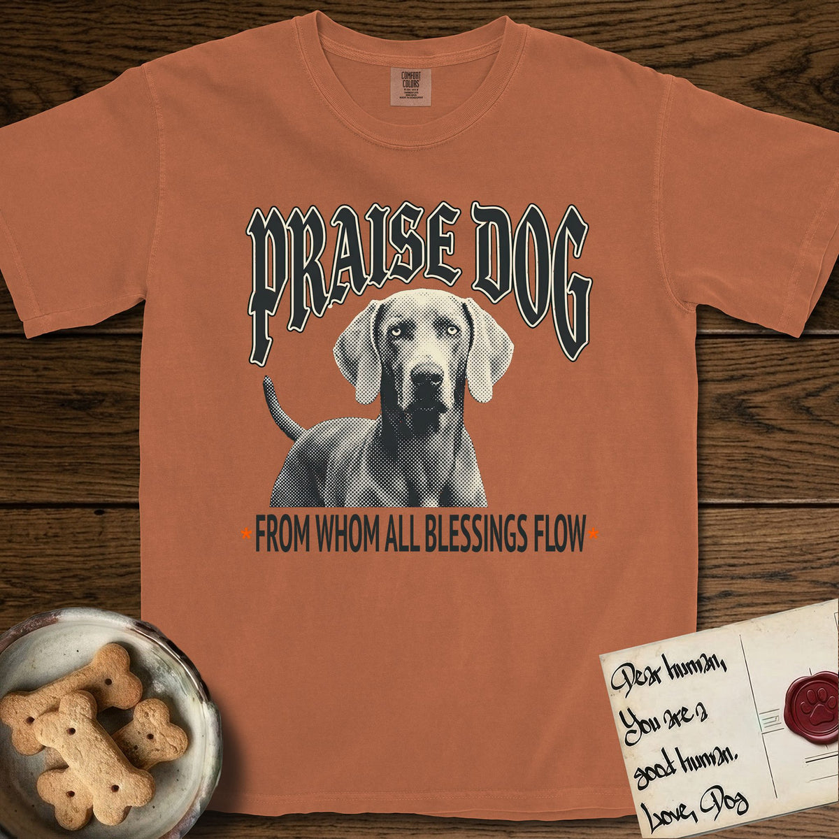 Praise Dog From Whom All Blessings Flow Weimaraner T-Shirt flat lay in Yam, featuring a gothic halftone poster with a Weimaraner staring straight ahead beneath heavy blackletter lettering and the words Praise Dog From Whom All Blessings Flow.