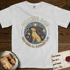 Praise Dog From Whom All Blessings Flow Yellow Lab T-Shirt flat lay in White, featuring a warm vintage circular emblem with an upward-gazing Yellow Lab, a sunburst, and a devotional border of small hearts and stars.