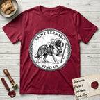 Patron Saint Medallion Saint Bernard T-Shirt flat lay in Antique Cherry Red, featuring a vintage engraving coin medallion of a haloed Saint Bernard carrying a child across a mountain pass, with the petition FIND US.