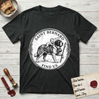 Patron Saint Medallion Saint Bernard T-Shirt flat lay in Black, featuring a vintage engraving coin medallion of a haloed Saint Bernard carrying a child across a mountain pass, with the petition FIND US.