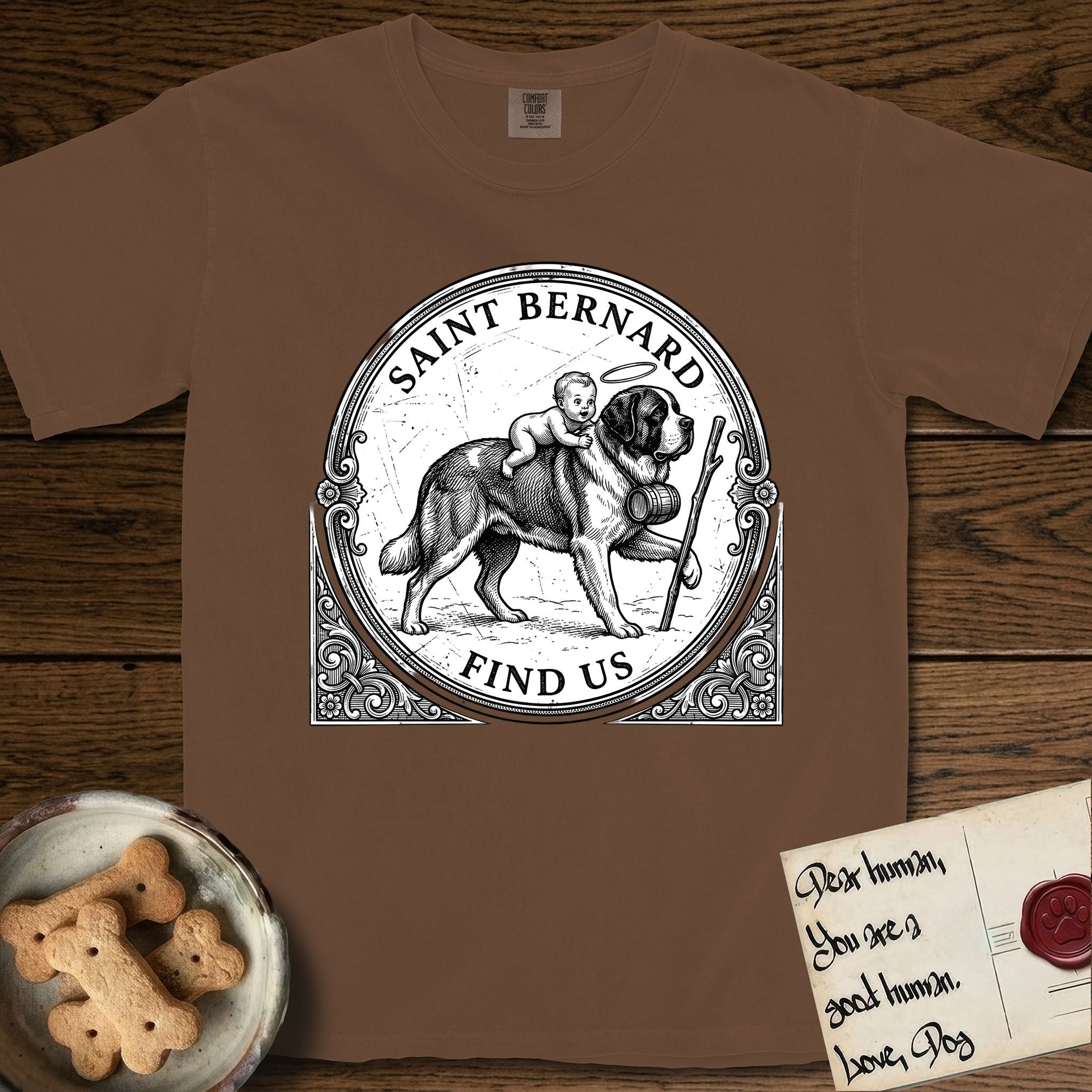 Patron Saint Medallion Saint Bernard T-Shirt flat lay in Espresso, featuring a vintage engraving coin medallion of a haloed Saint Bernard carrying a child across a mountain pass, with the petition FIND US.