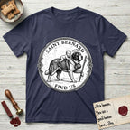 Patron Saint Medallion Saint Bernard T-Shirt flat lay in Navy, featuring a vintage engraving coin medallion of a haloed Saint Bernard carrying a child across a mountain pass, with the petition FIND US.
