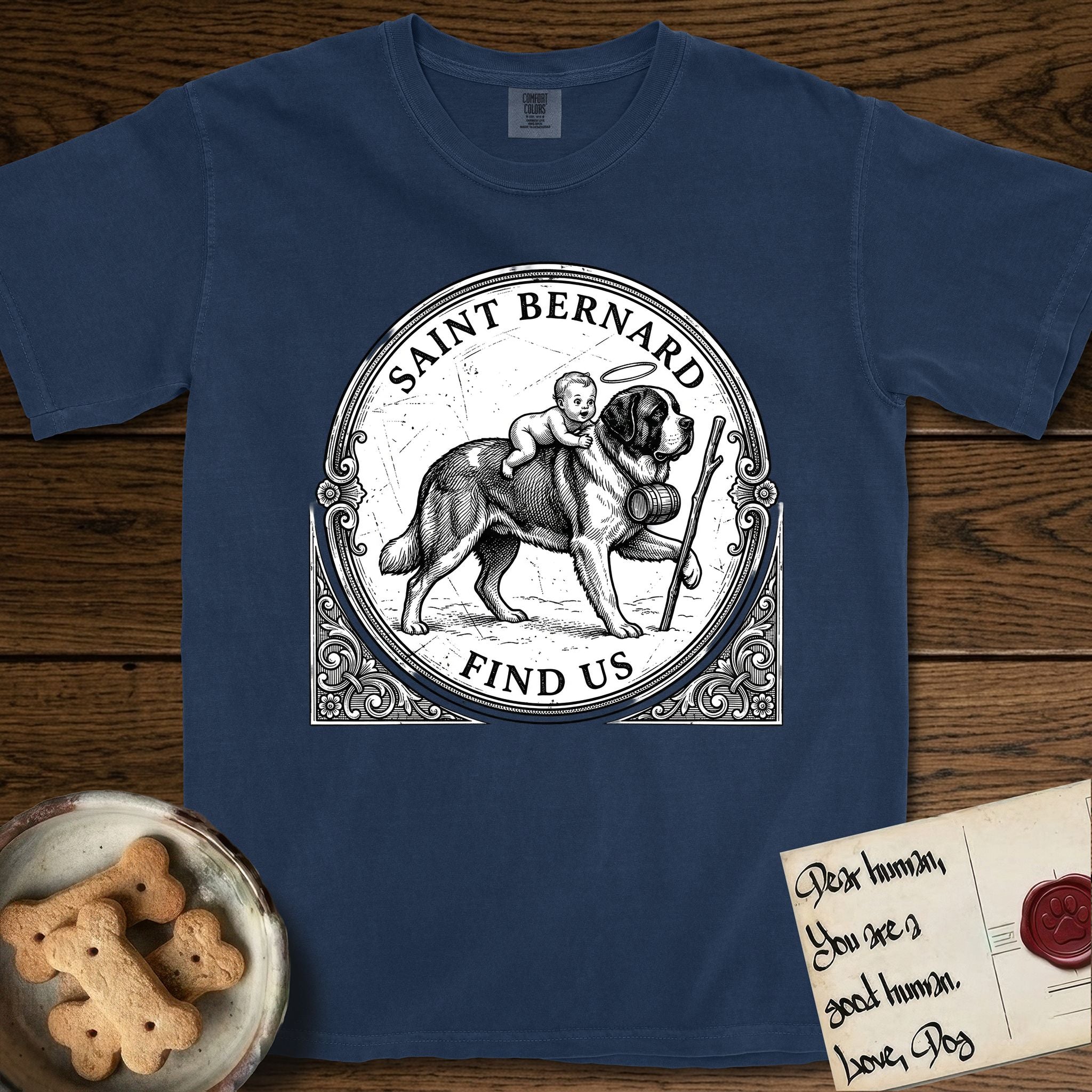 Patron Saint Medallion Saint Bernard T-Shirt flat lay in True Navy, featuring a vintage engraving coin medallion of a haloed Saint Bernard carrying a child across a mountain pass, with the petition FIND US.