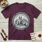 Patron Saint Medallion Saint Biscuit T-Shirt flat lay in Maroon, featuring a vintage engraving coin medallion of a haloed Golden Retriever with a devotee resting against her and an open book, with the petition HEAL US.