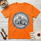 Patron Saint Medallion Saint Biscuit T-Shirt flat lay in Orange, featuring a vintage engraving coin medallion of a haloed Golden Retriever with a devotee resting against her and an open book, with the petition HEAL US.