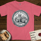 Patron Saint Medallion Saint Biscuit T-Shirt flat lay in Watermelon, featuring a vintage engraving coin medallion of a haloed Golden Retriever with a devotee resting against her and an open book, with the petition HEAL US.