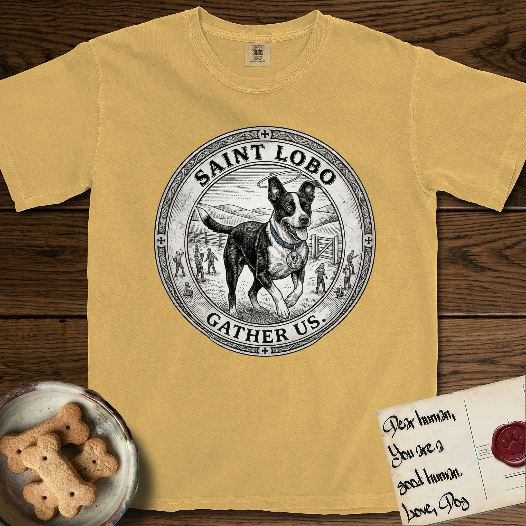 Patron Saint Medallion Saint Lobo T-Shirt flat lay in Mustard, featuring a vintage engraving coin medallion of haloed Saint Lobo running across open ground, with the petition GATHER US.