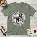 Patron Saint Medallion Saint Lobo T-Shirt flat lay in Sage, featuring a vintage engraving coin medallion of haloed Saint Lobo running across open ground, with the petition GATHER US.
