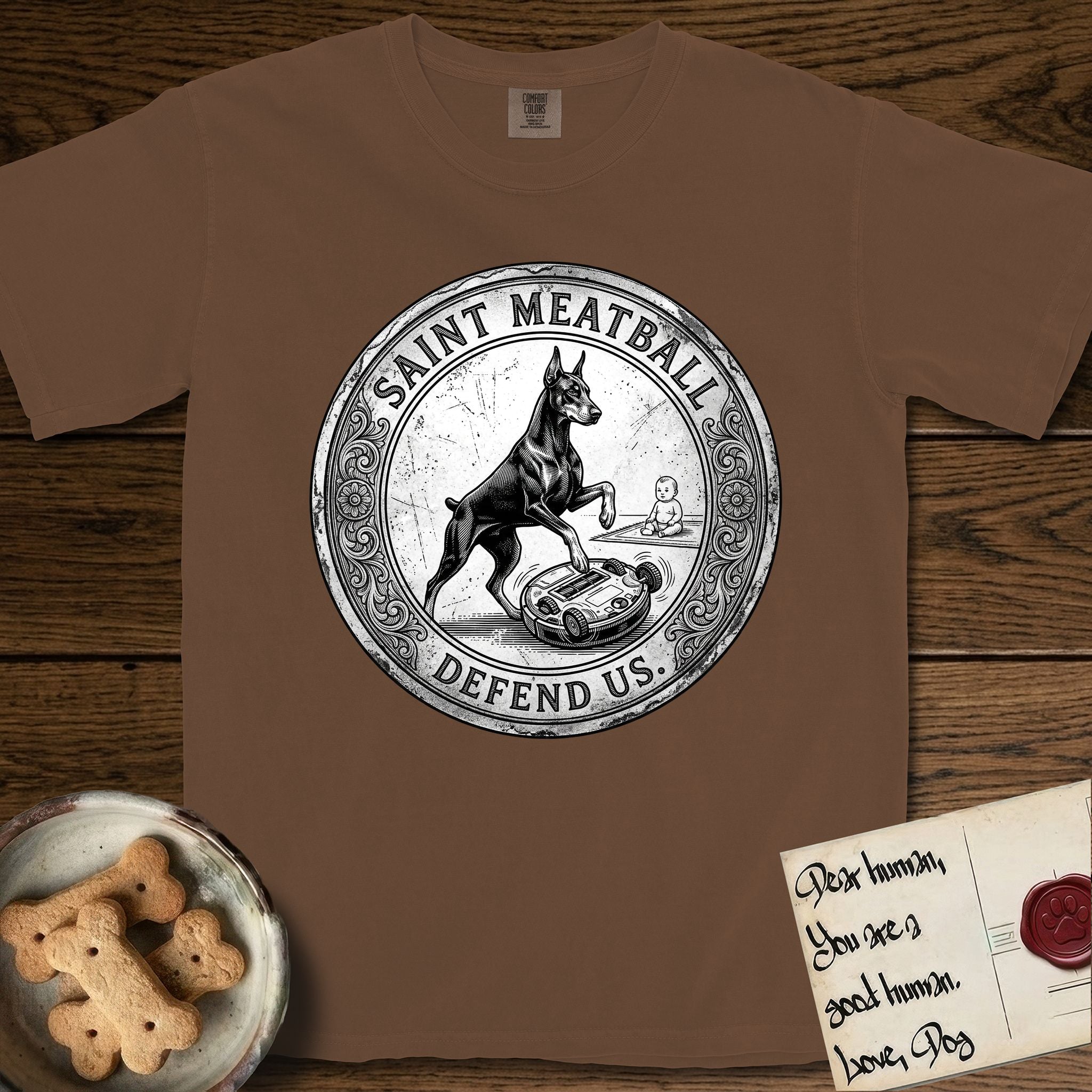 Patron Saint Medallion Saint Meatball T-Shirt flat lay in Espresso, featuring a vintage engraving coin medallion of a haloed Doberman rising on his hind legs, with the petition DEFEND US.