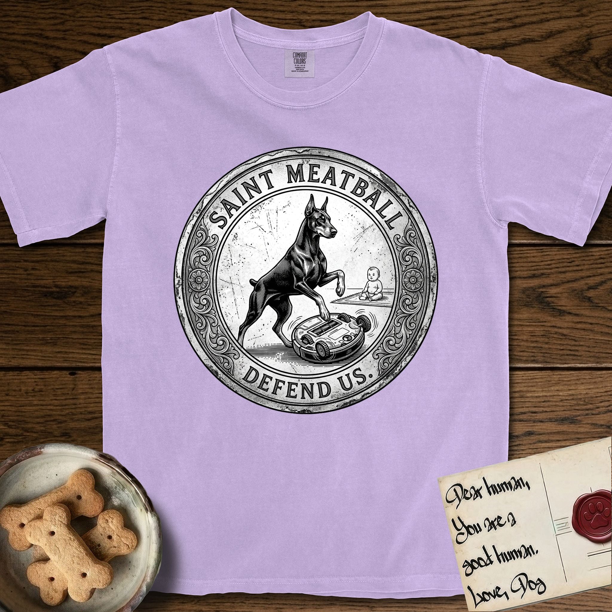 Patron Saint Medallion Saint Meatball T-Shirt flat lay in Orchid, featuring a vintage engraving coin medallion of a haloed Doberman rising on his hind legs, with the petition DEFEND US.