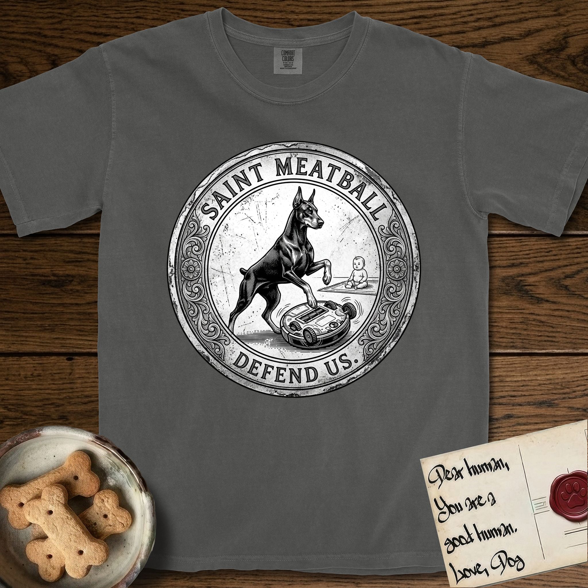 Patron Saint Medallion Saint Meatball T-Shirt flat lay in Pepper, featuring a vintage engraving coin medallion of a haloed Doberman rising on his hind legs, with the petition DEFEND US.