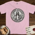 Patron Saint Medallion Saint Noodles T-Shirt flat lay in Blossom, featuring a vintage engraving coin medallion of a haloed Basset Hound with a staff and a child at her side, with the petition GUIDE US.