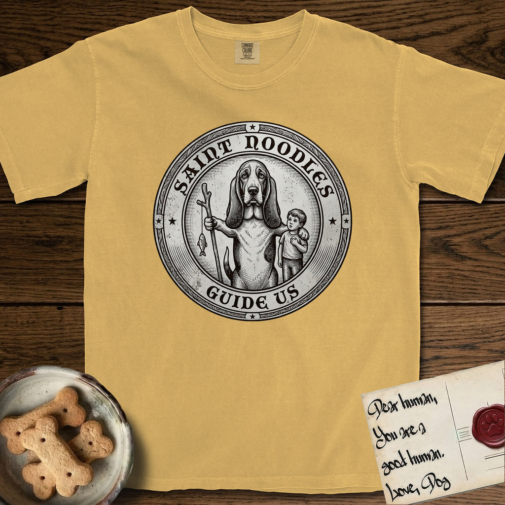 Patron Saint Medallion Saint Noodles T-Shirt flat lay in Mustard, featuring a vintage engraving coin medallion of a haloed Basset Hound with a staff and a child at her side, with the petition GUIDE US.