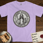 Patron Saint Medallion Saint Noodles T-Shirt flat lay in Orchid, featuring a vintage engraving coin medallion of a haloed Basset Hound with a staff and a child at her side, with the petition GUIDE US.