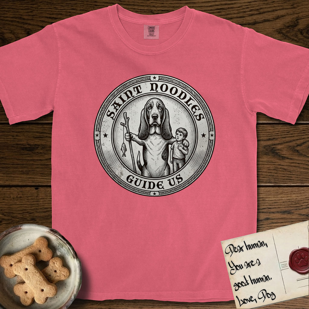 Patron Saint Medallion Saint Noodles T-Shirt flat lay in Watermelon, featuring a vintage engraving coin medallion of a haloed Basset Hound with a staff and a child at her side, with the petition GUIDE US.