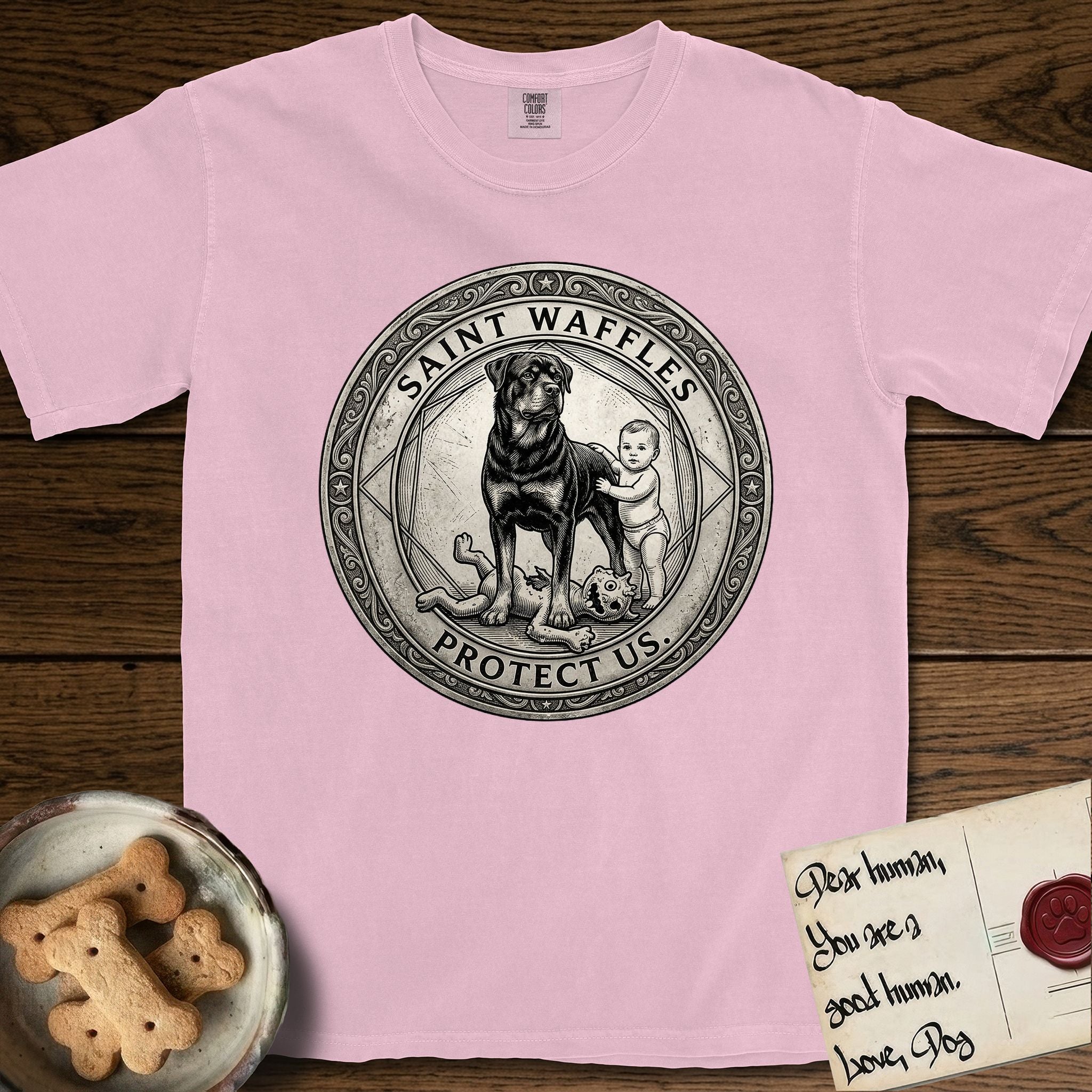Patron Saint Medallion Saint Waffles T-Shirt flat lay in Blossom, featuring a vintage engraving coin medallion of a haloed Rottweiler standing guard over a small child, with the petition PROTECT US.