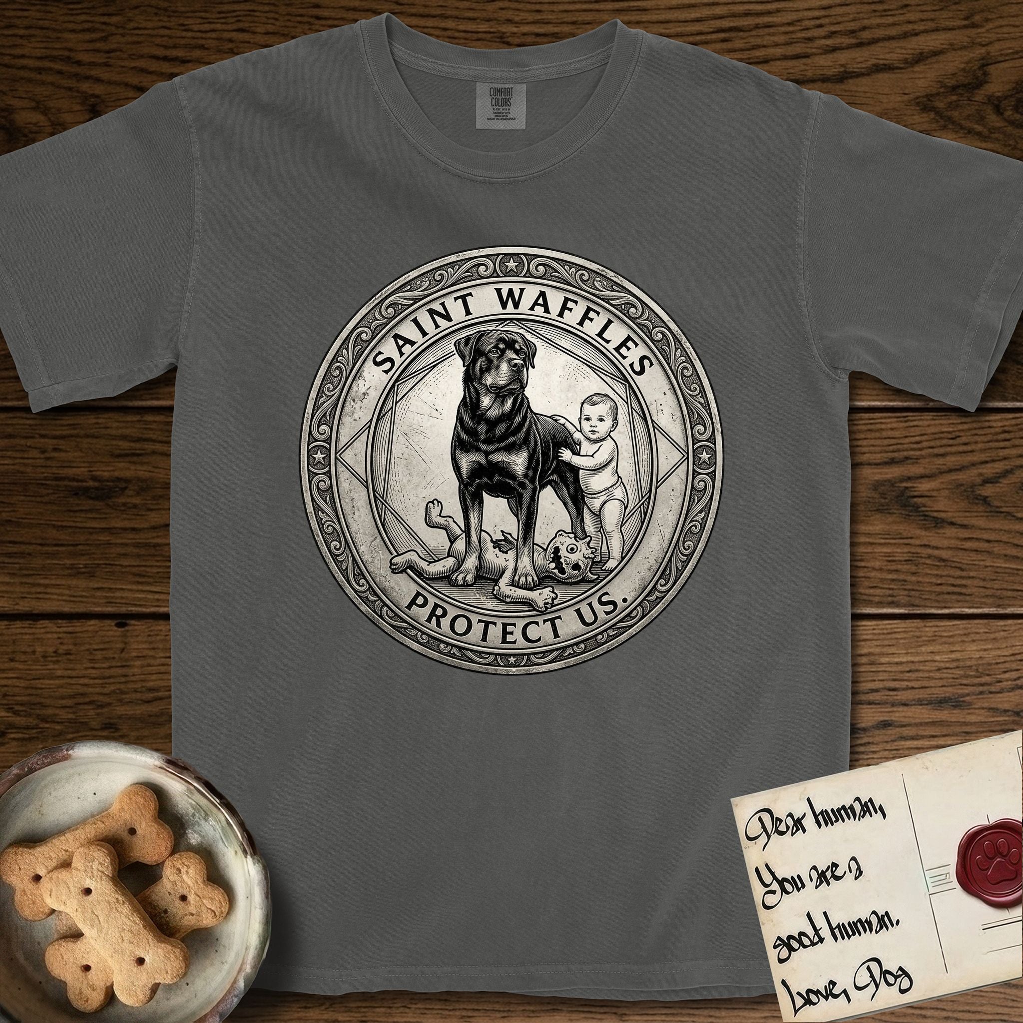 Patron Saint Medallion Saint Waffles T-Shirt flat lay in Pepper, featuring a vintage engraving coin medallion of a haloed Rottweiler standing guard over a small child, with the petition PROTECT US.