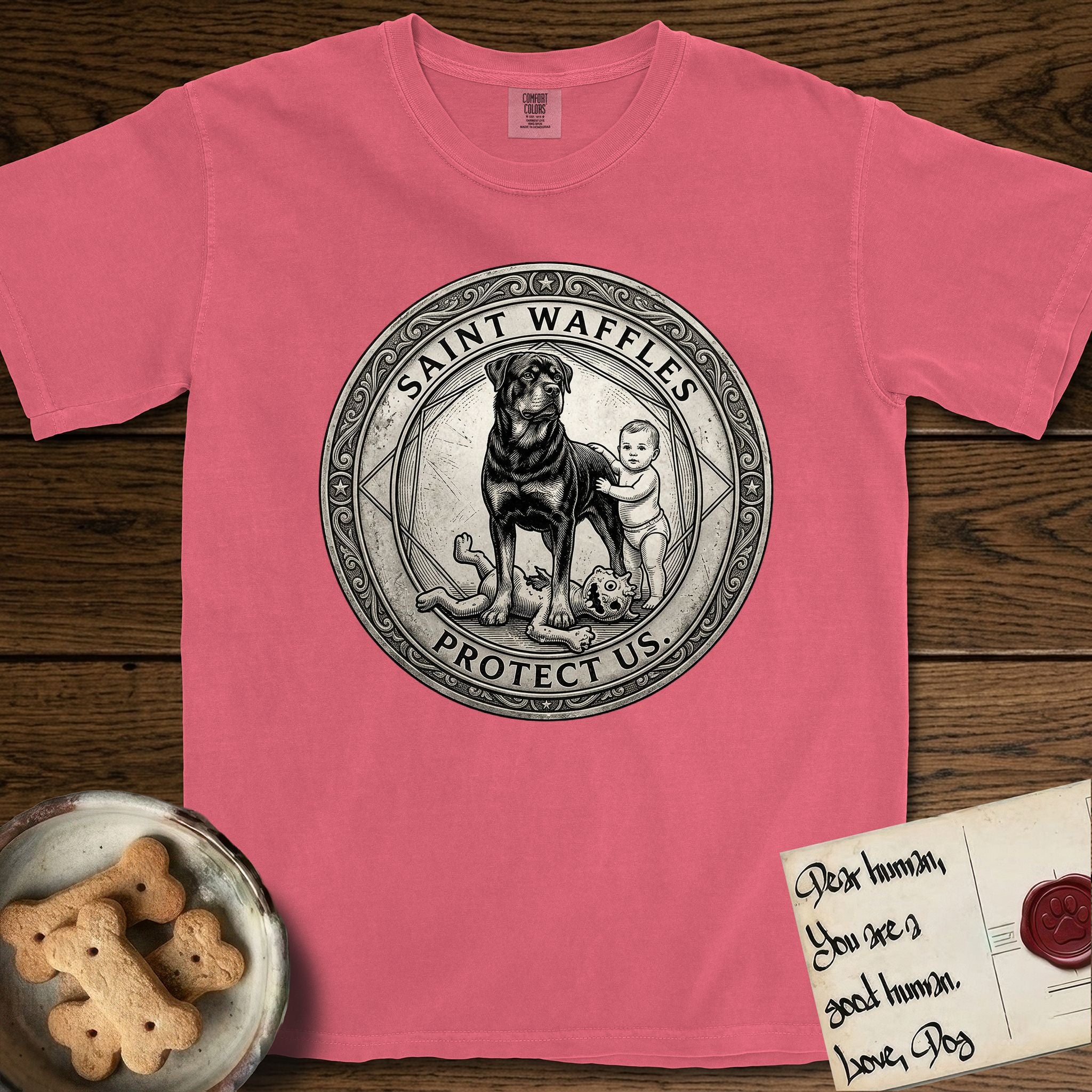 Patron Saint Medallion Saint Waffles T-Shirt flat lay in Watermelon, featuring a vintage engraving coin medallion of a haloed Rottweiler standing guard over a small child, with the petition PROTECT US.