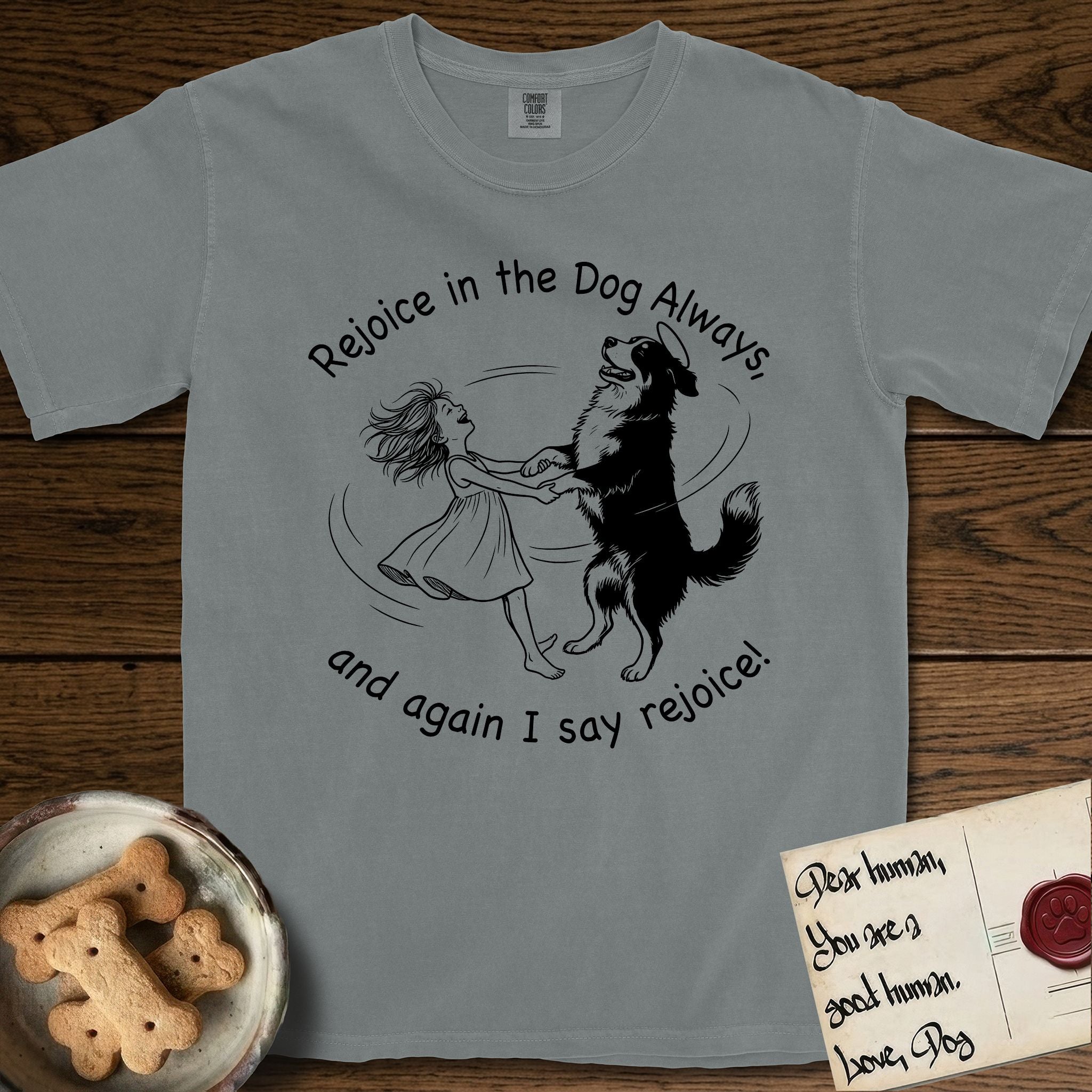 Rejoice in the Dog Bernese Mountain Dog T-Shirt flat lay in Granite, featuring a sparse pen-and-ink illustration of a girl and her Bernese Mountain Dog spinning together, her feet lifting off the ground.
