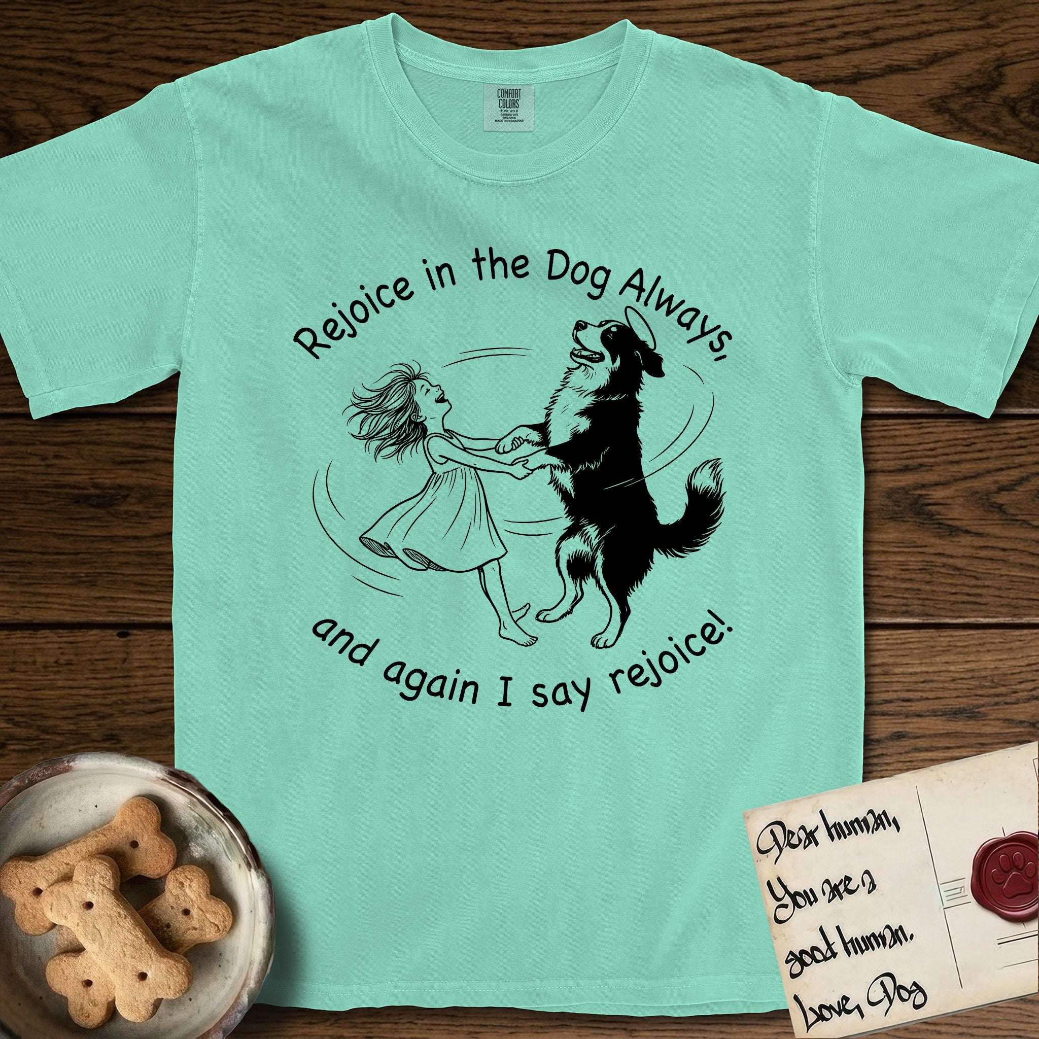 Rejoice in the Dog Bernese Mountain Dog T-Shirt flat lay in Island Reef, featuring a sparse pen-and-ink illustration of a girl and her Bernese Mountain Dog spinning together, her feet lifting off the ground.